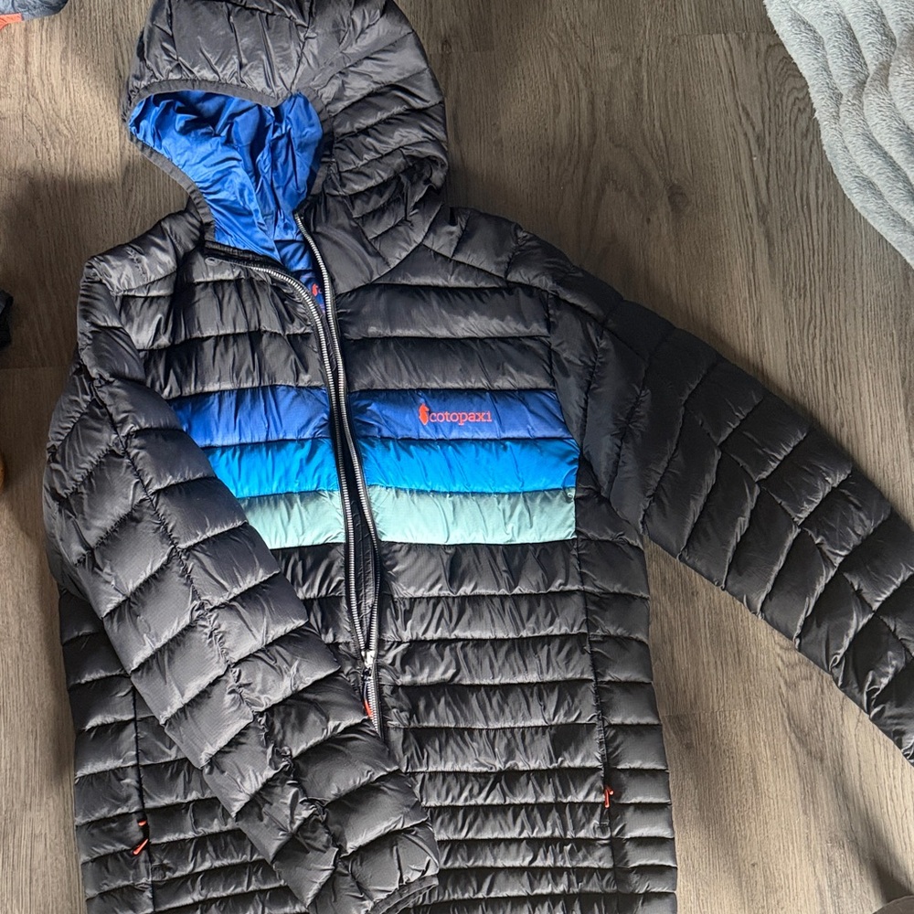 cotopaxi Black Hooded Puffer with Blue-to-Teal Chest Stripe